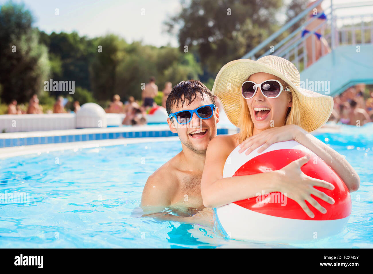 Beautiful young couple having fun outside in the swimming pool Stock Photo