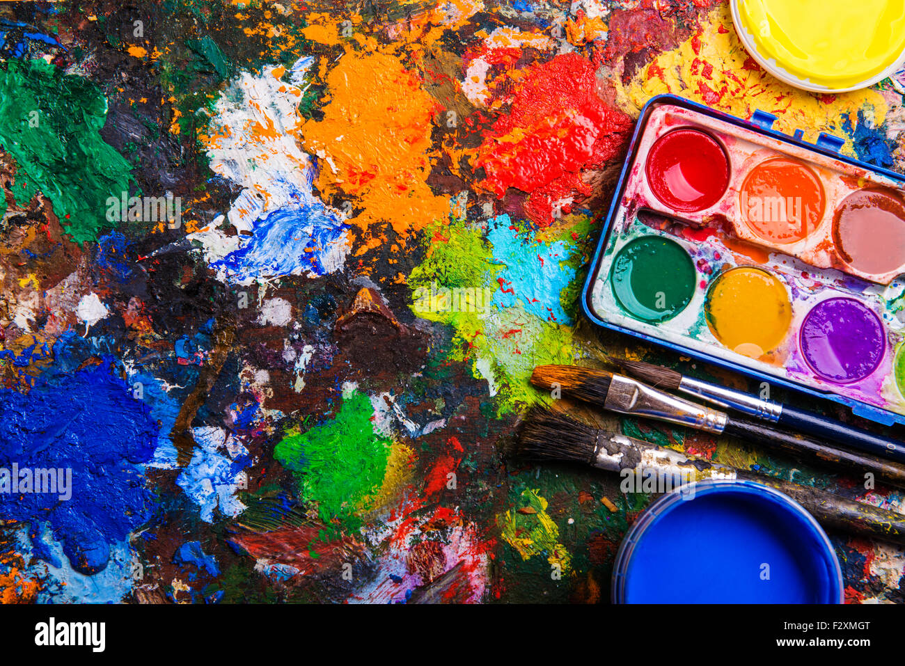 Desk of an artist with watercolor paints and paintbrushes. Stock Photo