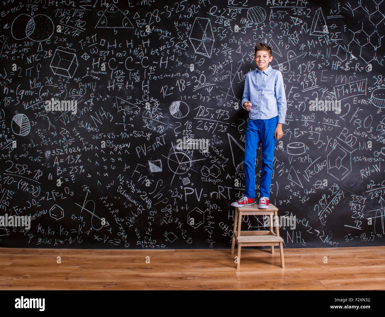 Young handsome school boy standing in front of big blackboard Stock Photo