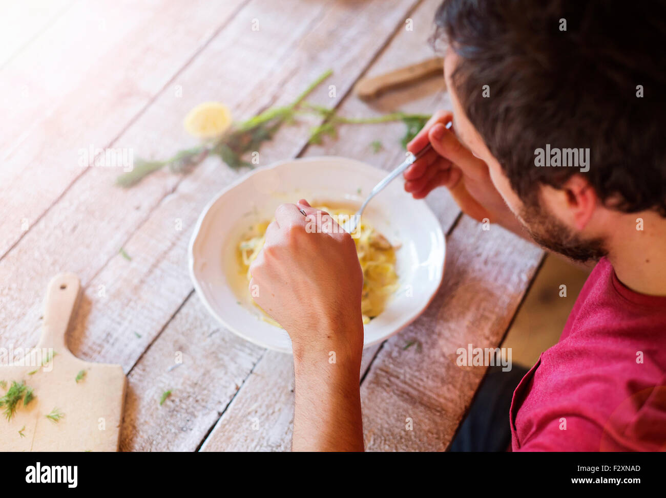 Young handsome man in the kitchen eating salmon tagliatelle Stock Photo