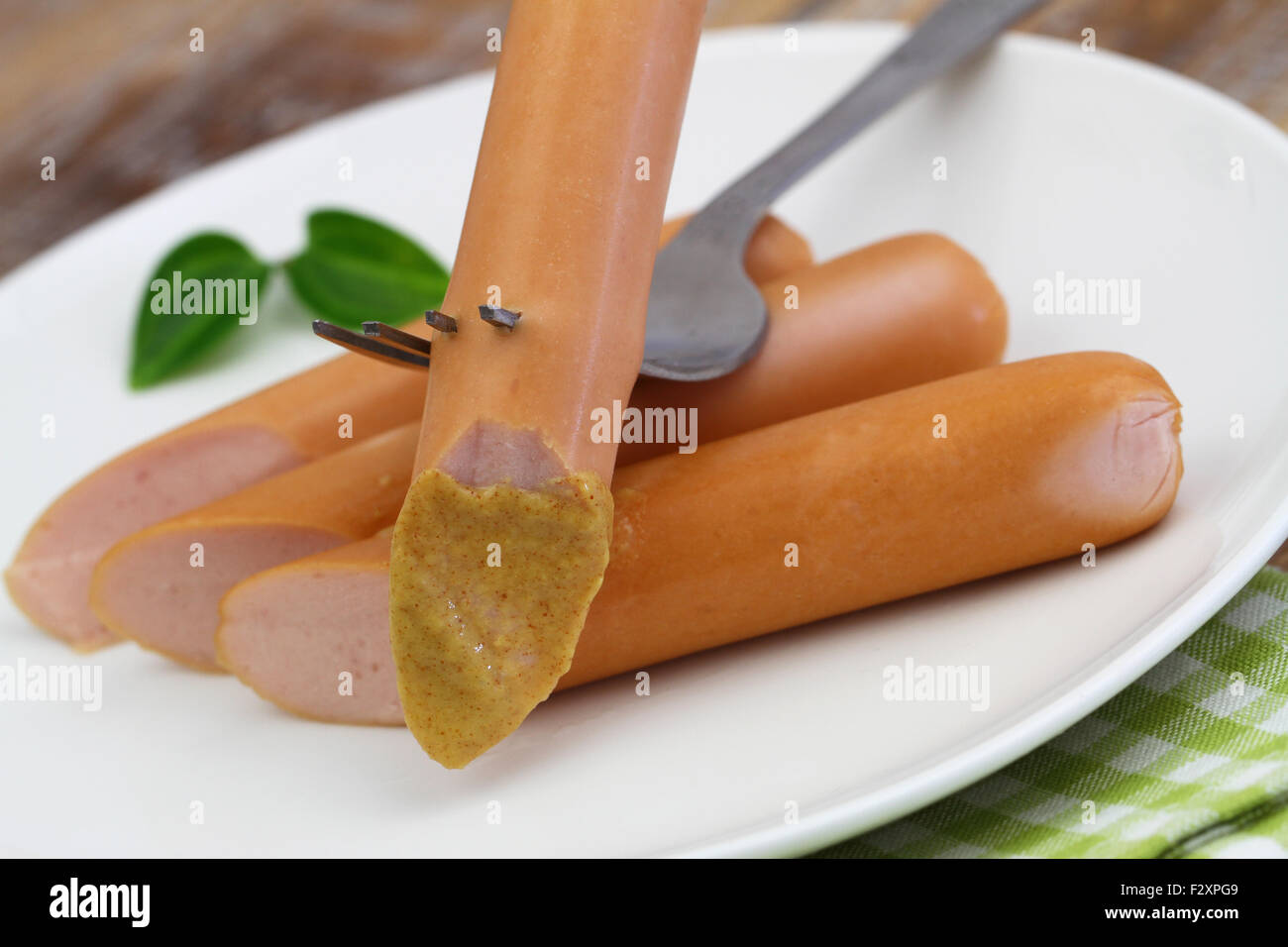 Frankfurter with mustard on fork, closeup Stock Photo