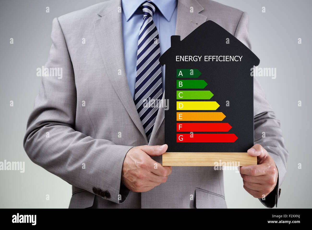 Businessman holding house shape blackboard with chalk energy efficiency rating chart concept for performance, efficiency and env Stock Photo