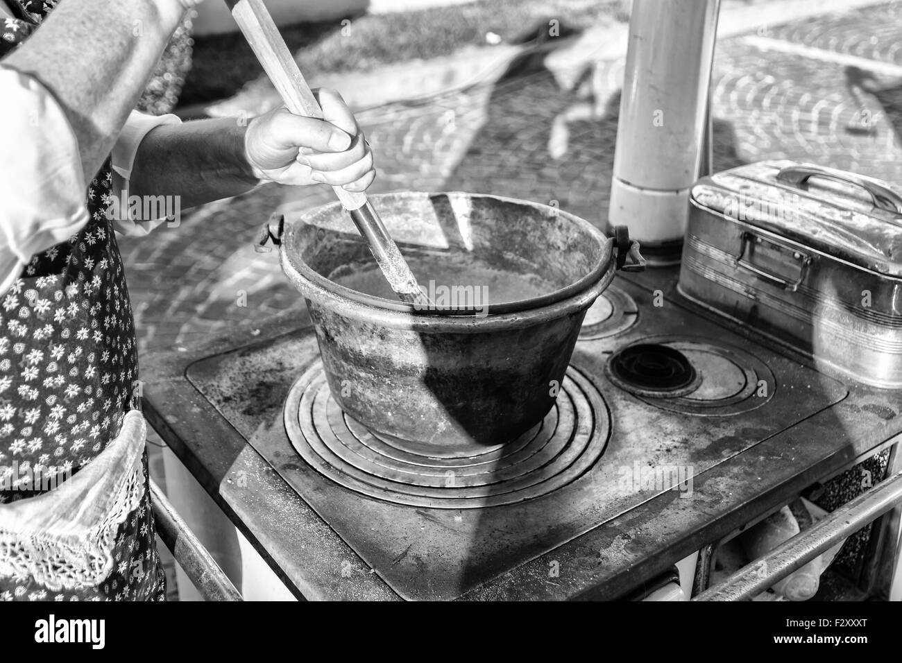 Cooking polenta in a copper pot on wood stove (dish of the Venetian tradition, Italy). Stock Photo