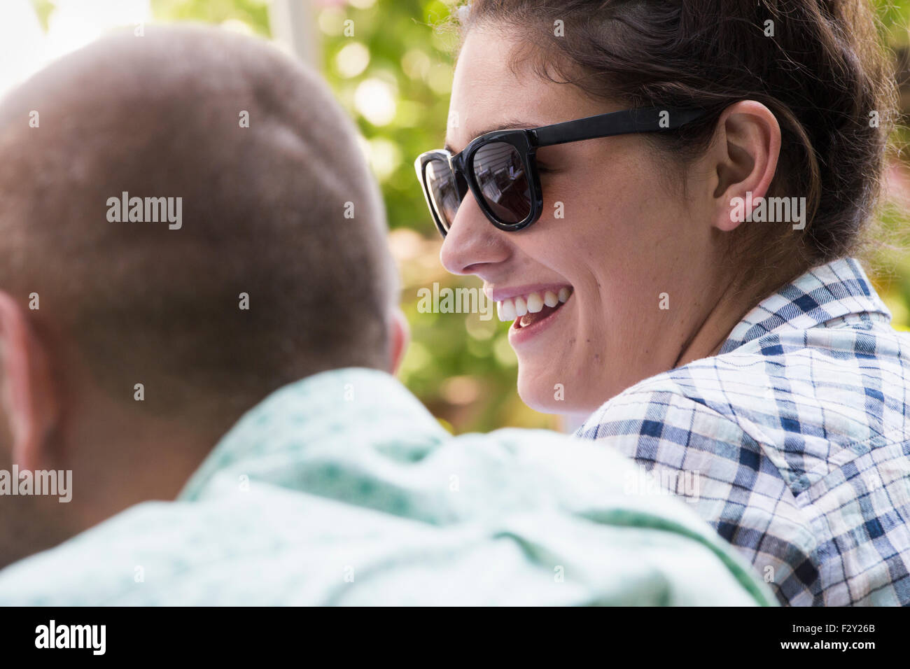 A young man and woman sitting side by side, smiling. Stock Photo