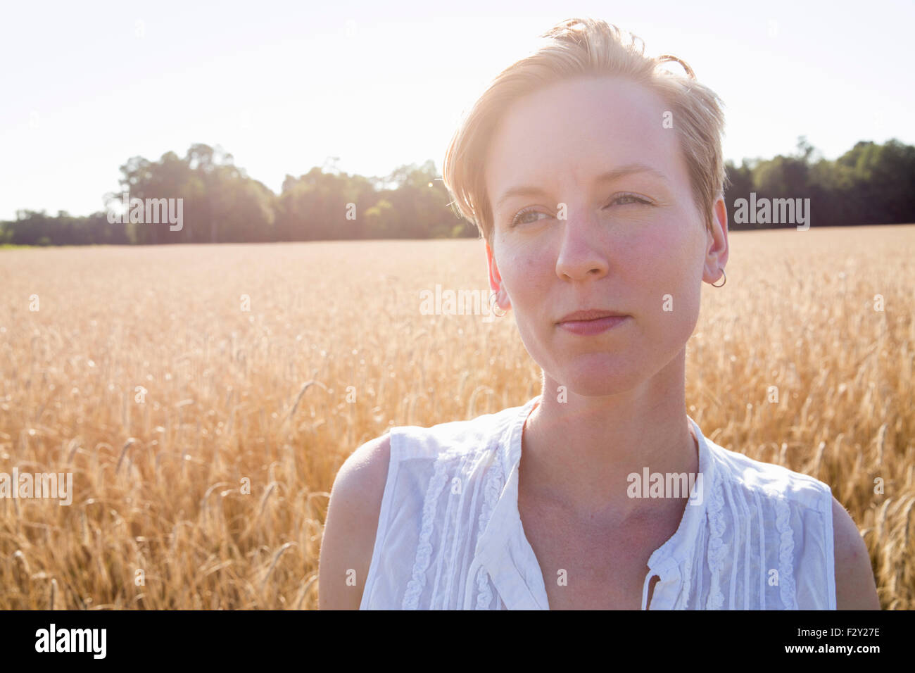 Head and shoulders portrait of a young woman standing in a cornfield. Stock Photo