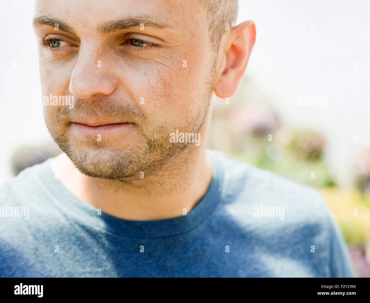 Head and shoulders portrait of a man with stubble in a blue teesirt. Stock Photo
