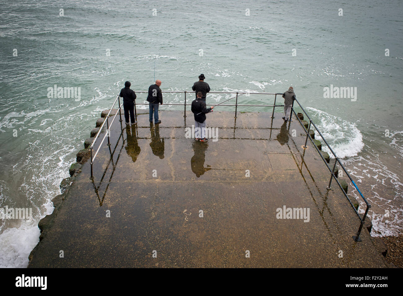 men fishing in the sea from a pier. Stock Photo