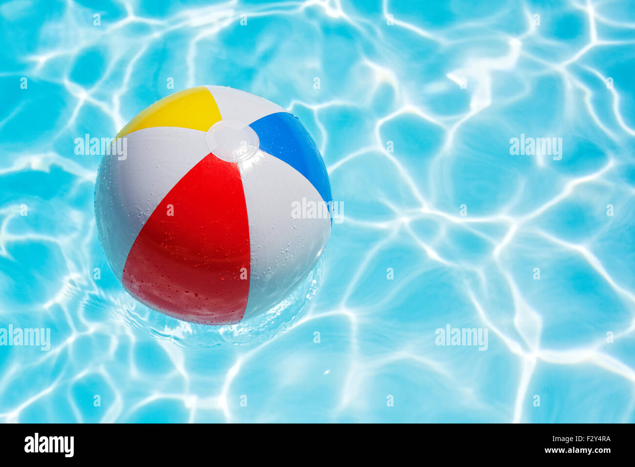 Beach ball floating in swimming pool abstract concept for summer vacations, relaxation and fun in the sunshine Stock Photo