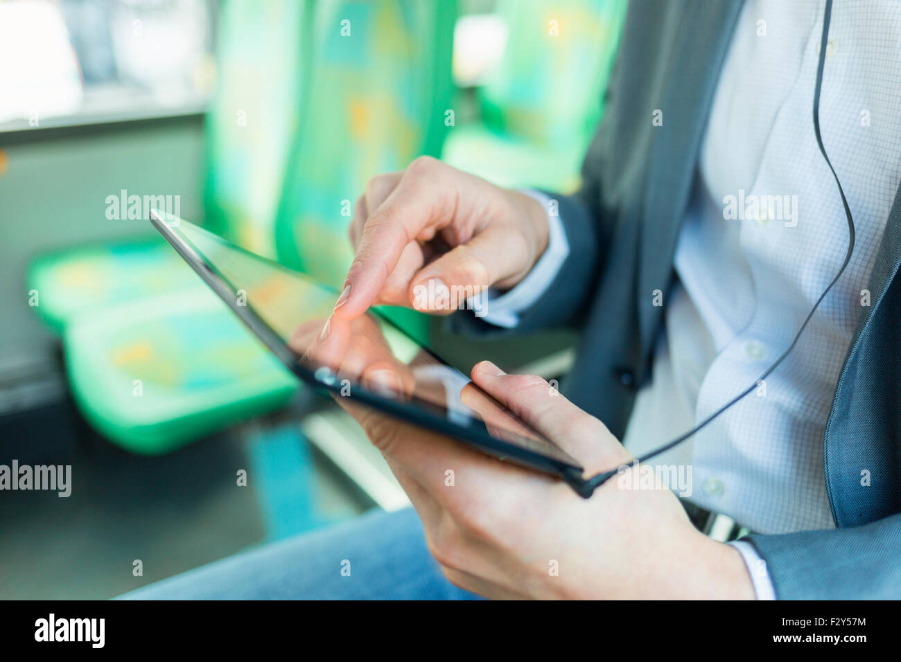 Man listening music with tablet pc. on bus. texting message. Close-up hands Stock Photo