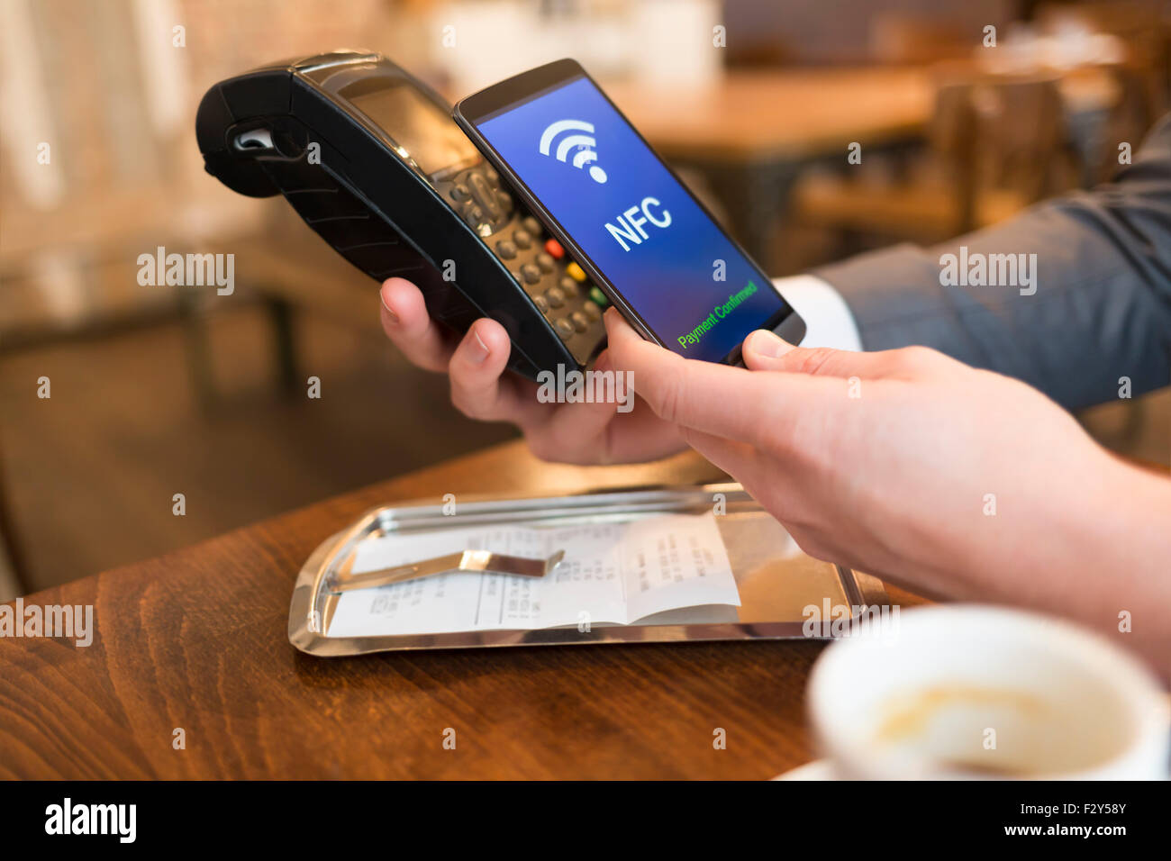 Man paying with NFC technology on mobile phone, in restaurant, bar, cafe Stock Photo