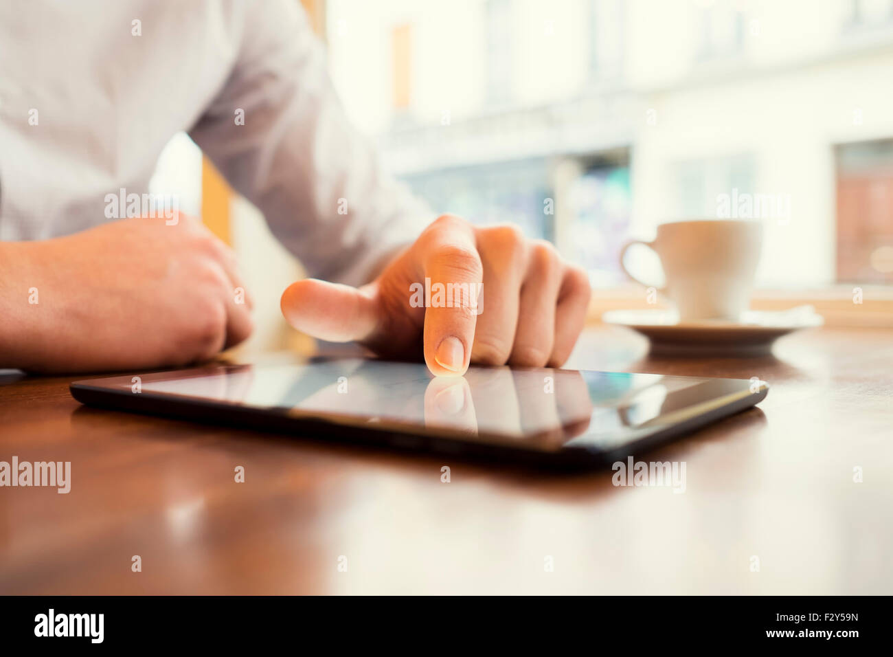 Man in a bar using tablet pc. Window background. Vintage filter Stock Photo