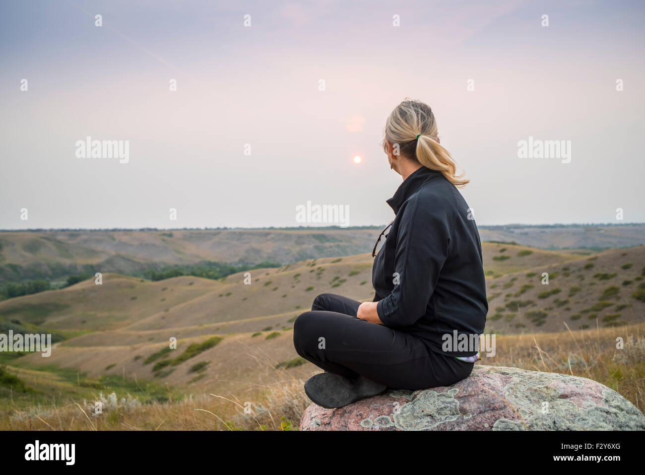 woman sitting on rock in coulees of southern alberta Stock Photo