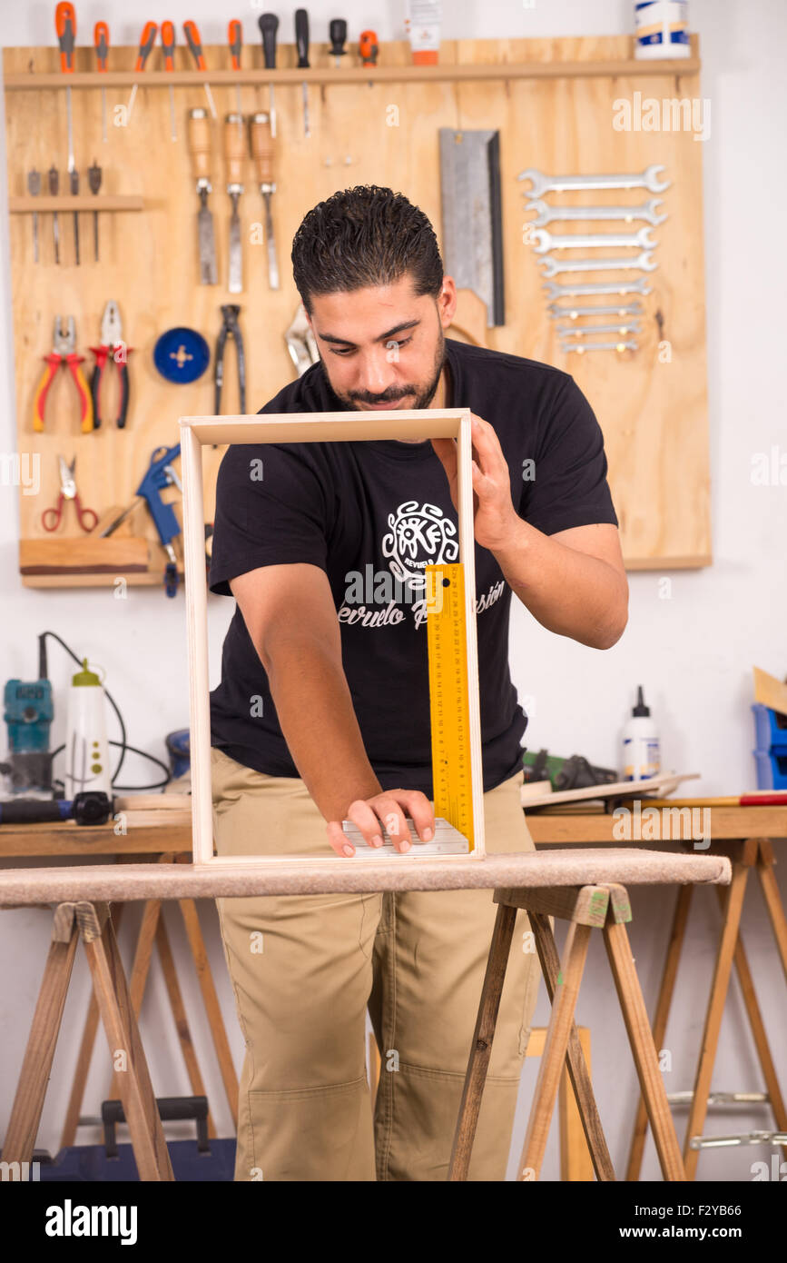 Skilled artisan measuring the frame of an unfinished percussion instrument Stock Photo