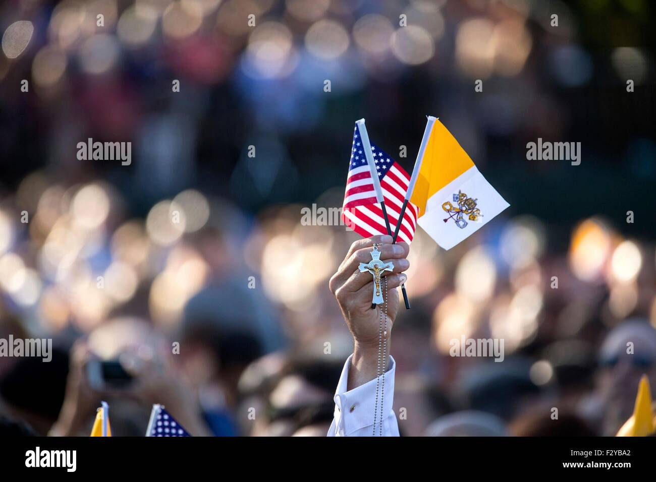 A guest for Pope Francis arrival ceremony on the South Lawn of the White House holds up the American flag, the Vatican City flag, and a cross September 23, 2015 in Washington, DC. This is the first visit by Pope Francis to the United States. Stock Photo