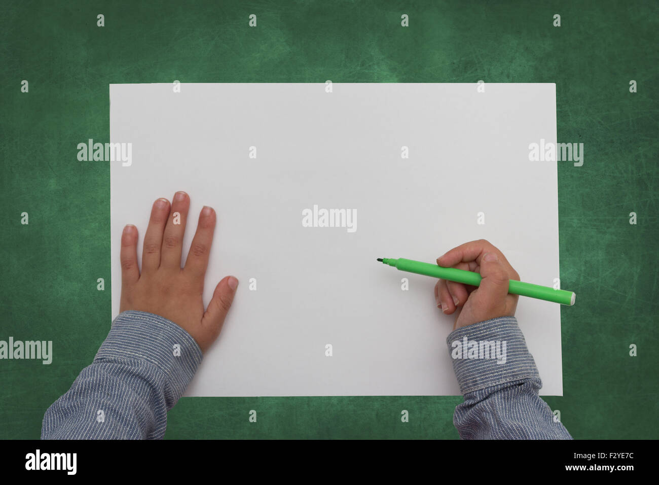 child holding crayon on blank sheet of paper Stock Photo