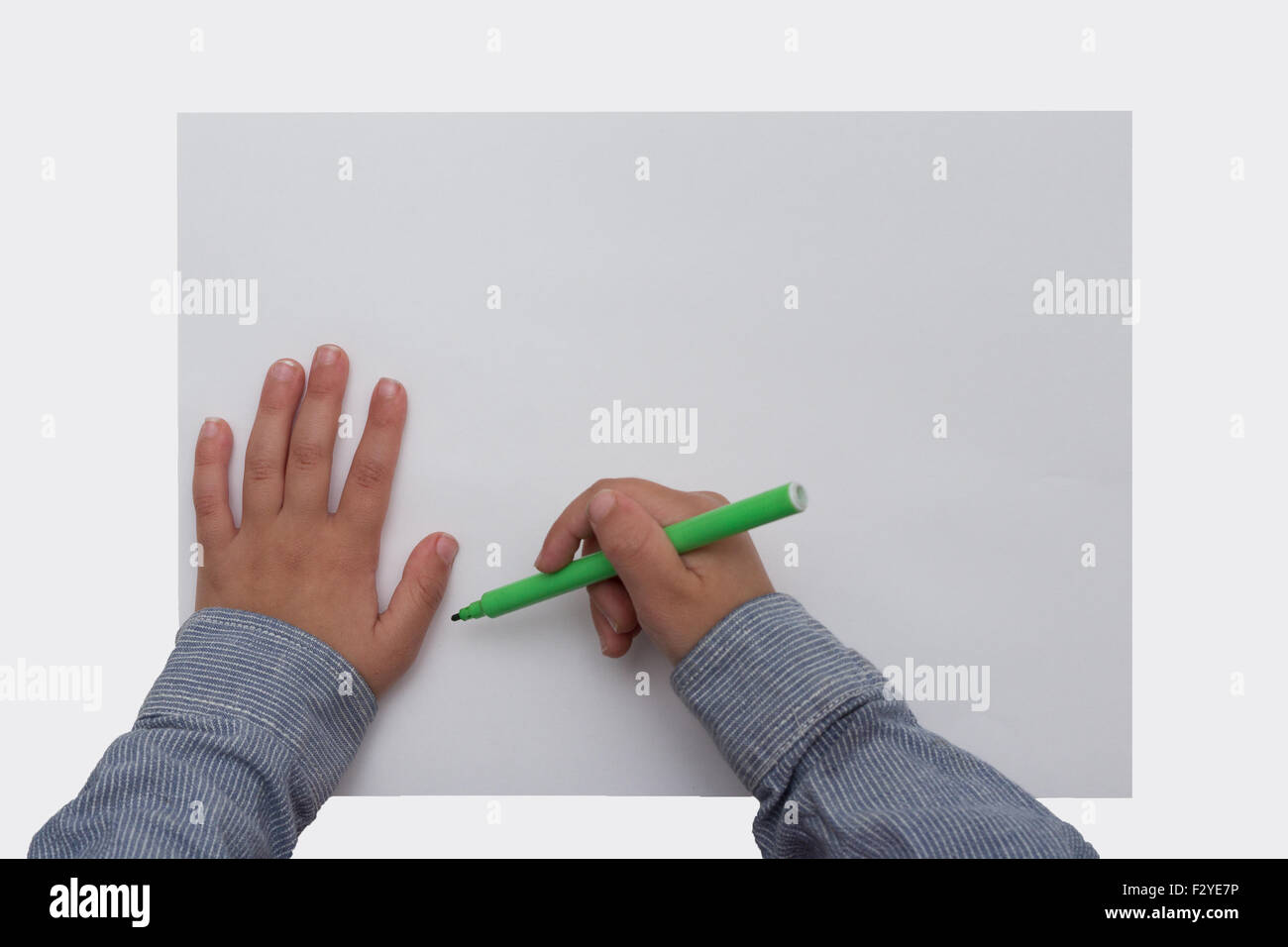 child holding pen on blank sheet of paper Stock Photo