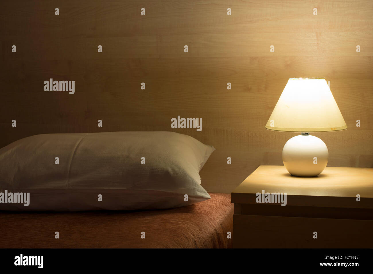 hotel room interior with illuminated bed light on wooden table Stock Photo