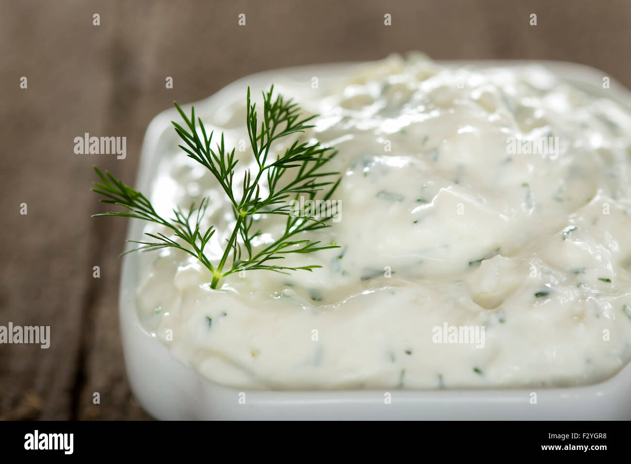 Bowl of fresh garlic cheese sauce on old rustic wooden background Stock Photo