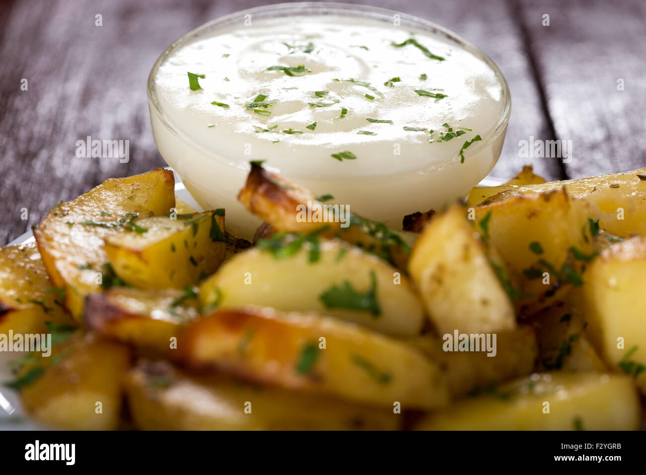Garlic sauce in bowl and some backed potatoes out of focus Stock Photo