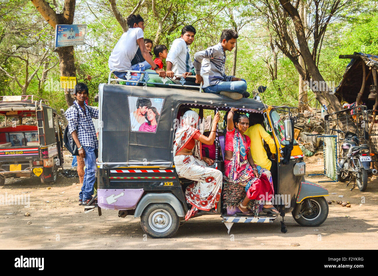 An auto-rickshaw overloaded with people, posing a threat to passengers and road users in Gujarat, India Stock Photo