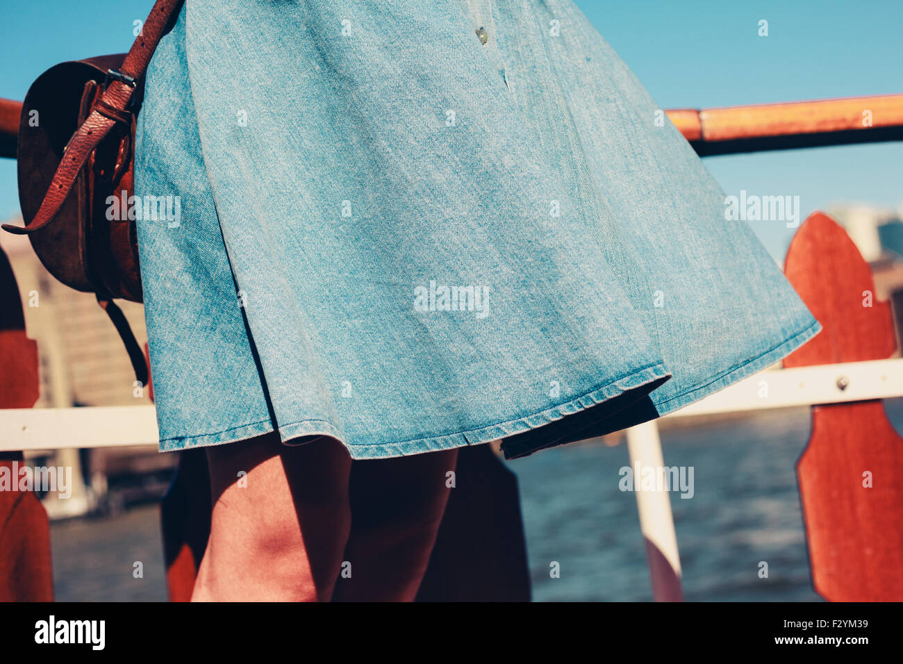 A young woman's skirt is blowing in the wind as she is standing on the deck of a boat cruising down the river Stock Photo