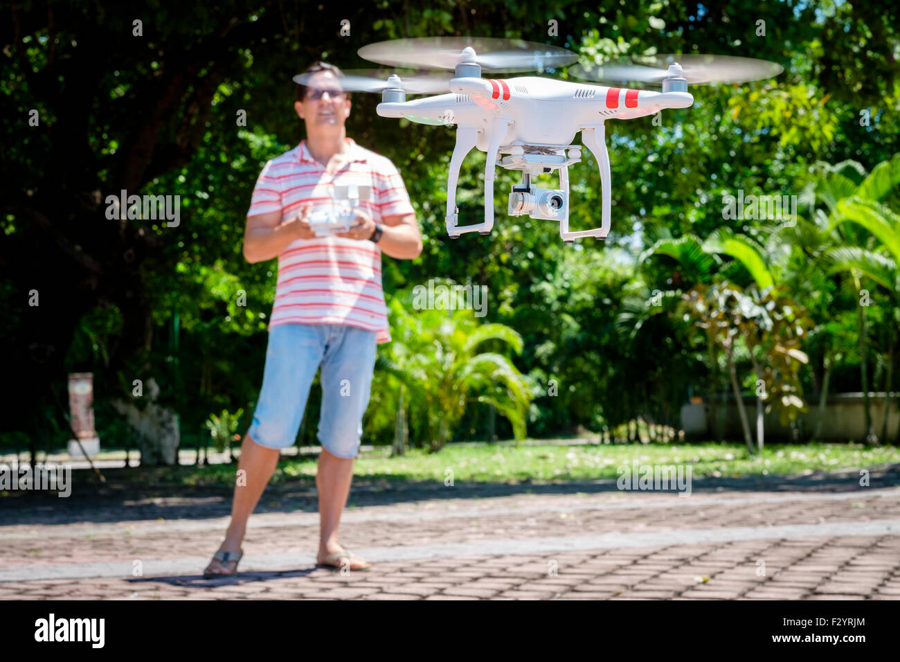 Caucasian man using remote control to operate a quadcopter drone hovering in air. Stock Photo
