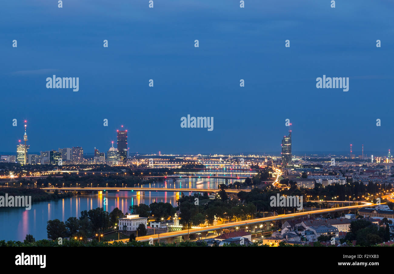 A view of buildings and bridges close to the Danube River in Vienna at night. There is space for text. Stock Photo