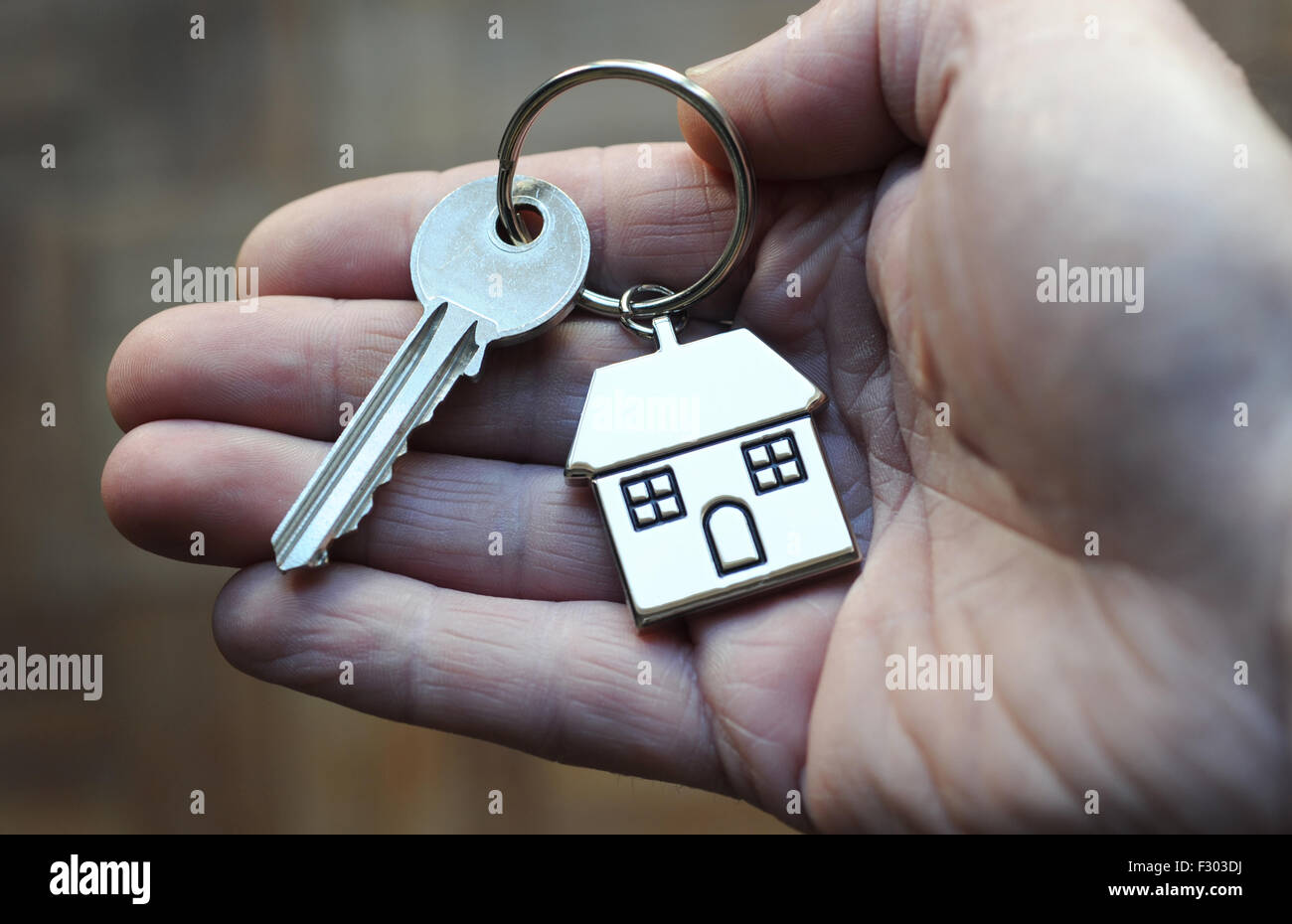 MANS HAND HOLDING HOUSE KEY AND FOB RE HOME BUYERS BUYING HOUSING LADDER PROPERTY MARKET MORTGAGES OWNERS OWNERSHIP RATES UK Stock Photo