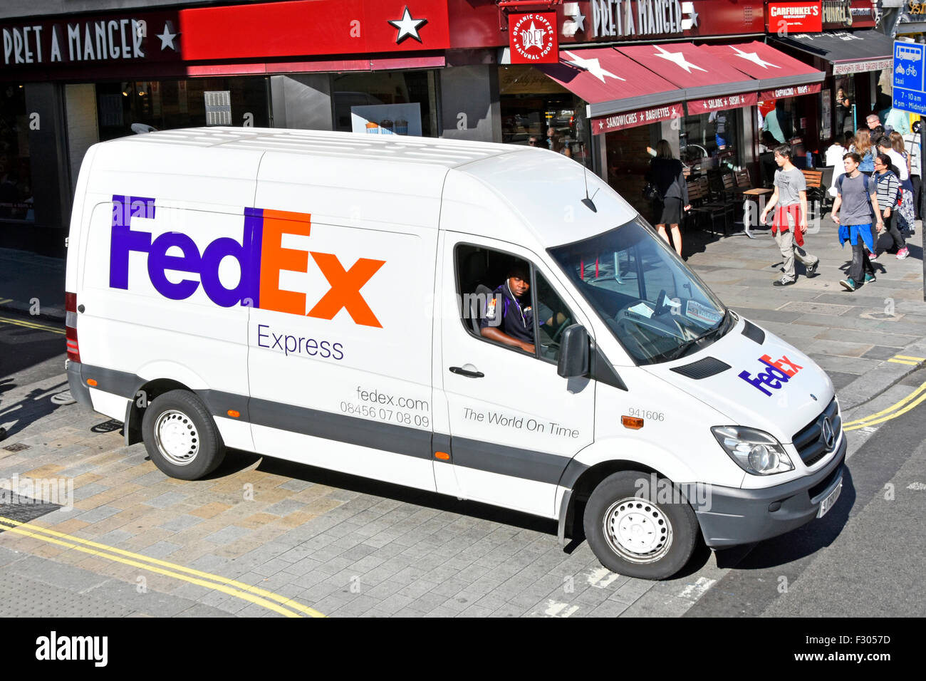 Aerial view looking down on white Fedex express parcels delivery van with brand logo & driver in sunny shopping street scene Strand London England UK Stock Photo