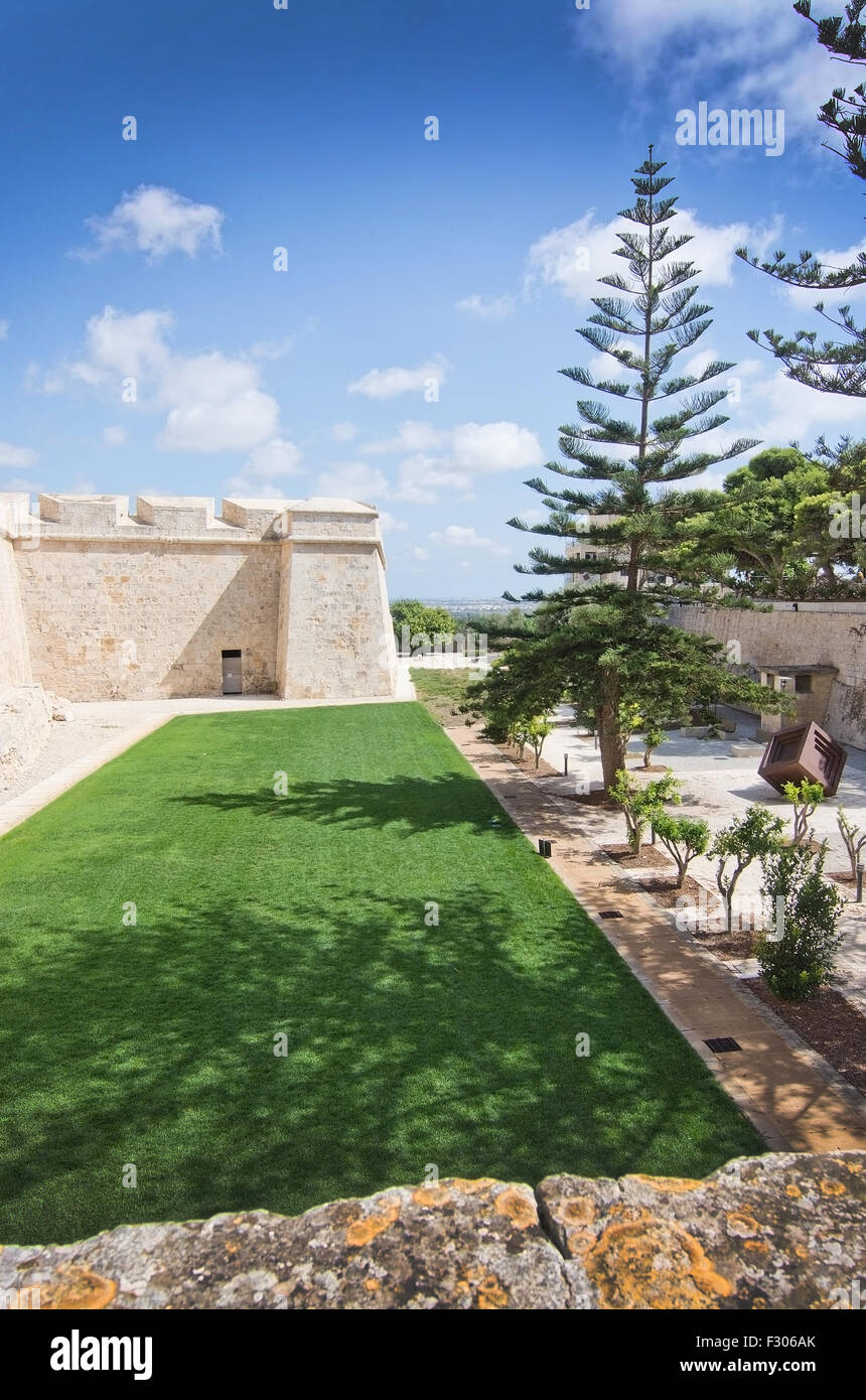 Old city walls and green well kept lawn on a sunny day in September in Mdina, Malta. Stock Photo