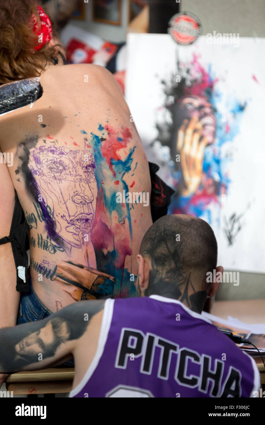 London, UK. 25th Sep, 2015. A woman getting her back tattoed a the Tattoo Lucky Hazzard stand at the London Tattoo Convention, Tobacco dock. Credit:  Simon Balson/Alamy Live News Stock Photo