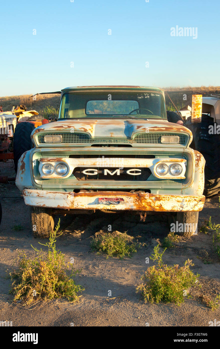 Rusted 1960 GMC pickup truck in junkyard at sunset, US, 2015. Stock Photo