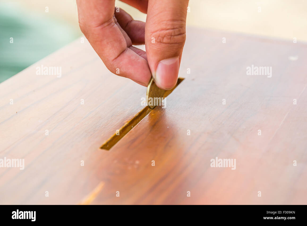 Male hand putting coin into a piggy bank Stock Photo - Alamy