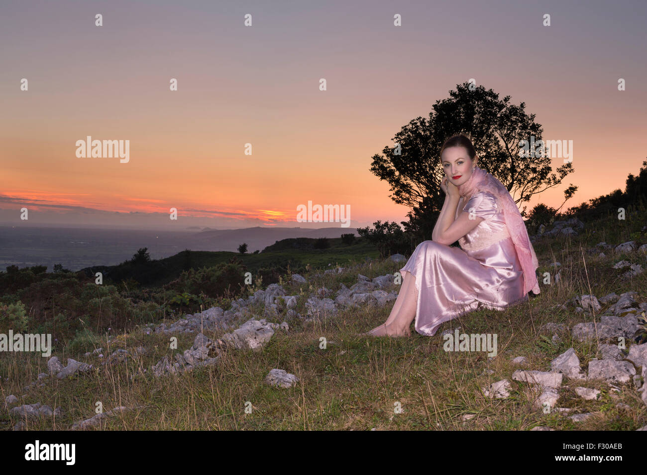 Woman dressed in 1940's style nightwear at dusk on Draycott Sleights, part of the Medip Hills. Stock Photo