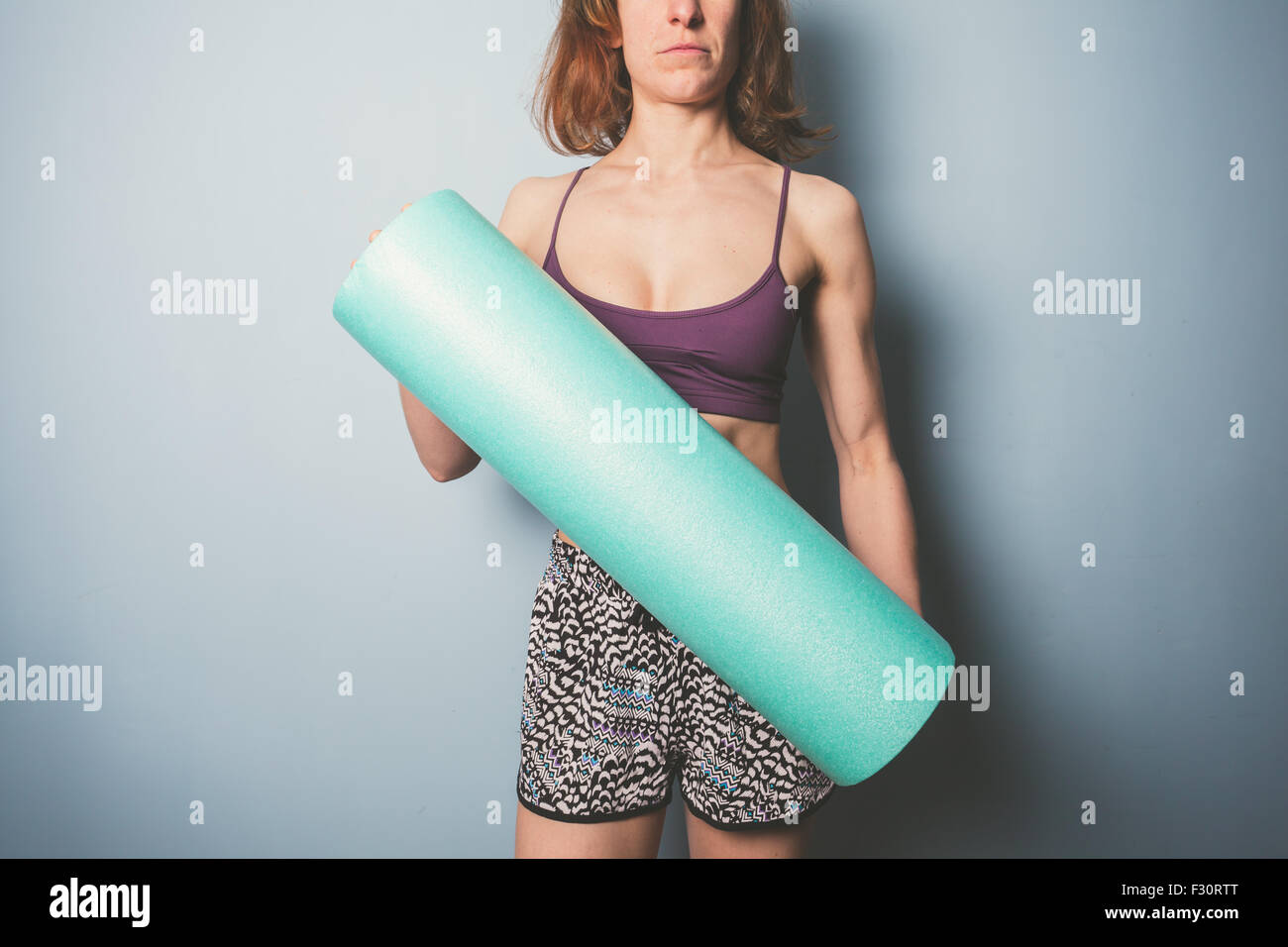 Athletic young woman is holding a foam roller for exercise Stock Photo ...