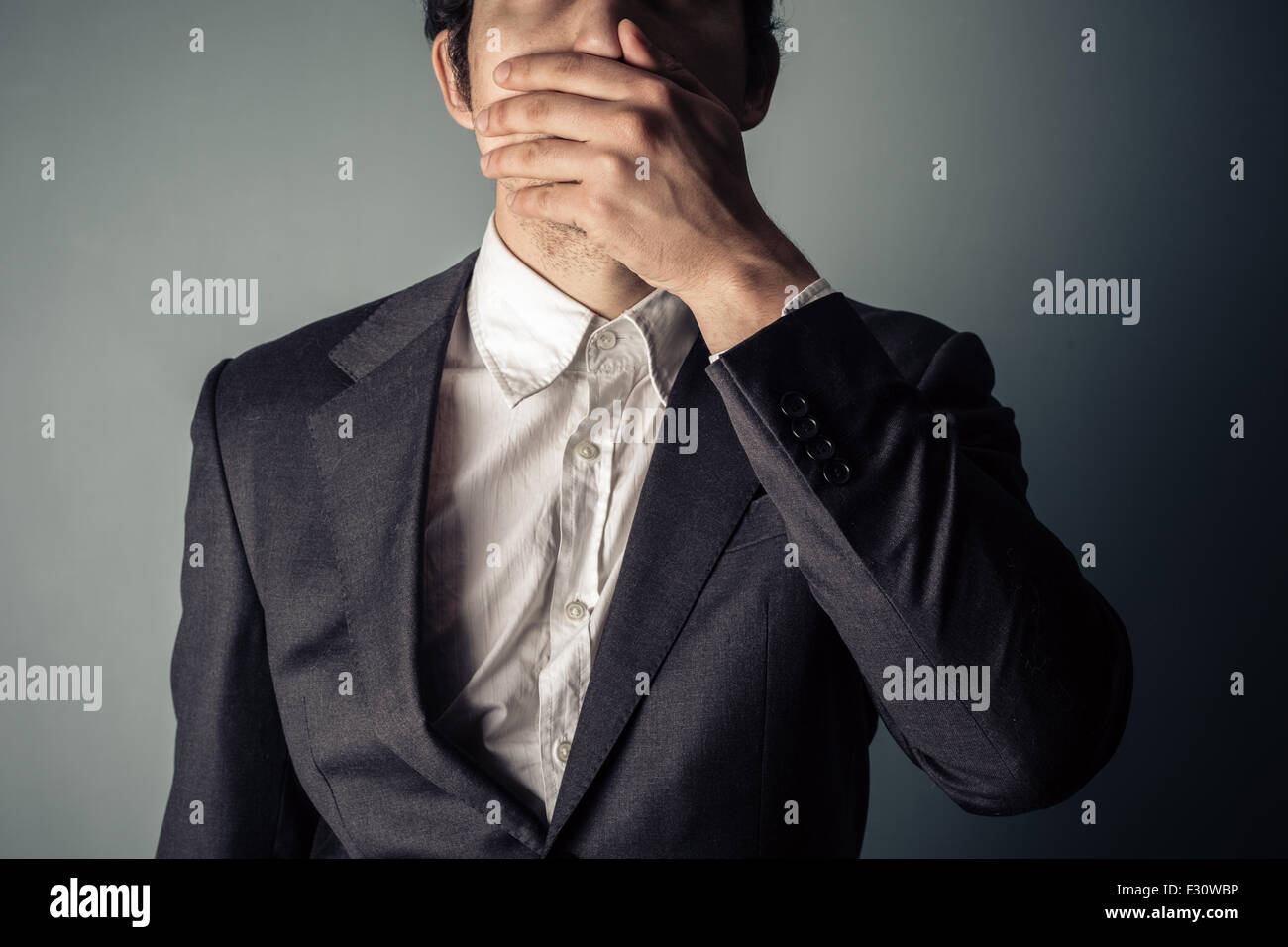 Shocked young businessman covering is mouth Stock Photo