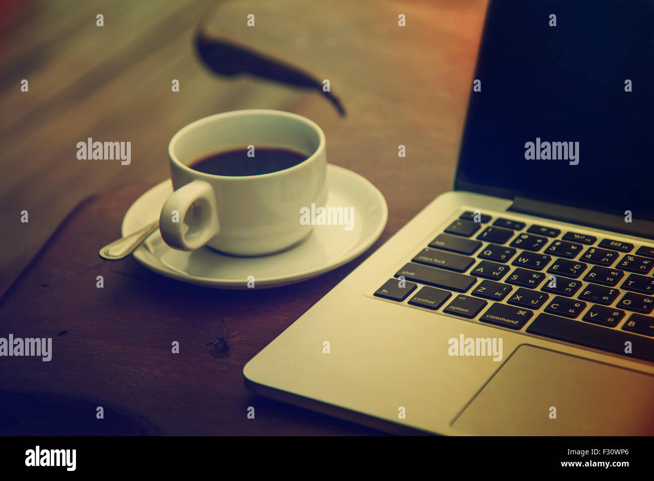 Black coffee in a white cup on a table with a computer. Stock Photo