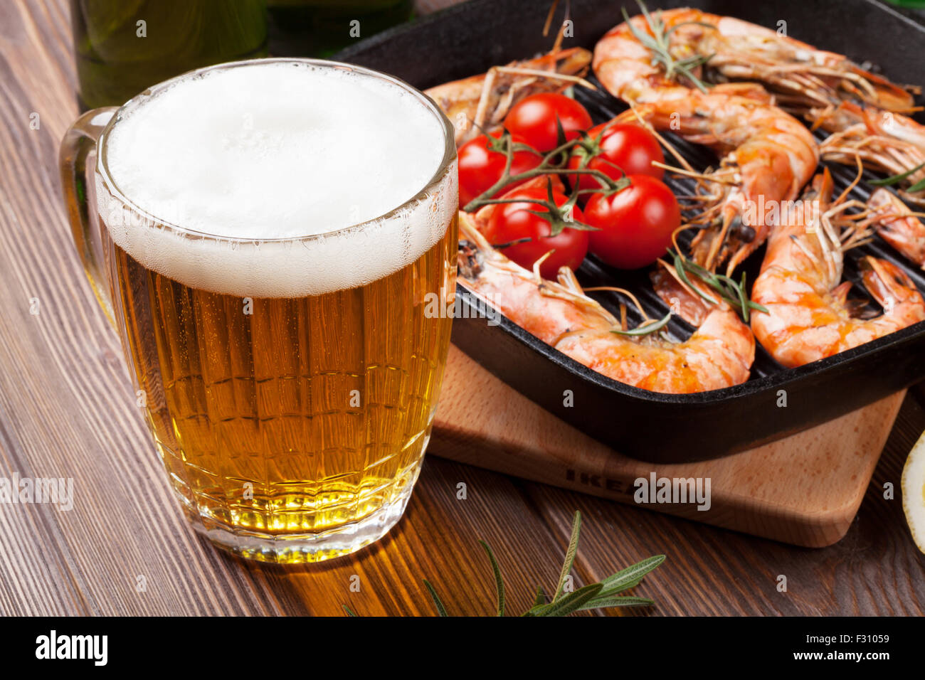 Beer mug and grilled shrimps on wooden table Stock Photo