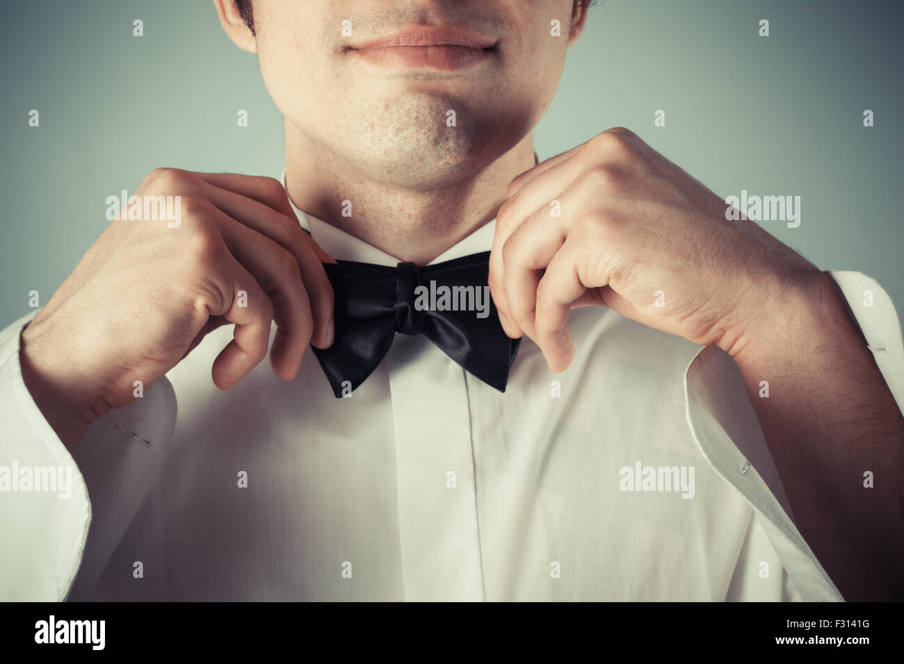 Closeup on a happy young man tying a bow tie Stock Photo - Alamy