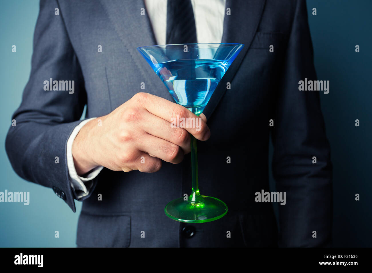 Young businessman is holding a tall cocktail glass Stock Photo - Alamy