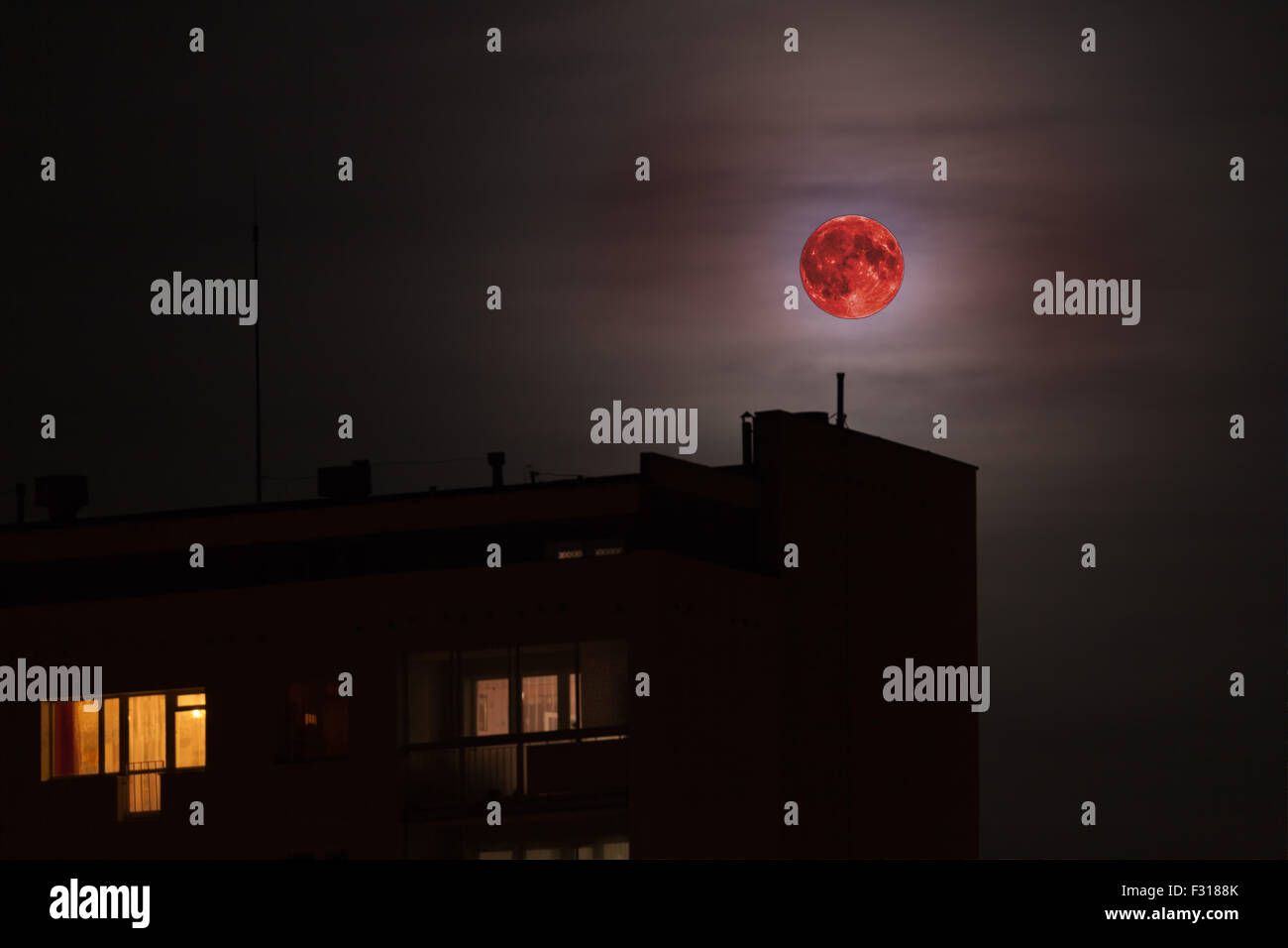 Red full moon in red color also called bloodmoon on the background of building. Stock Photo