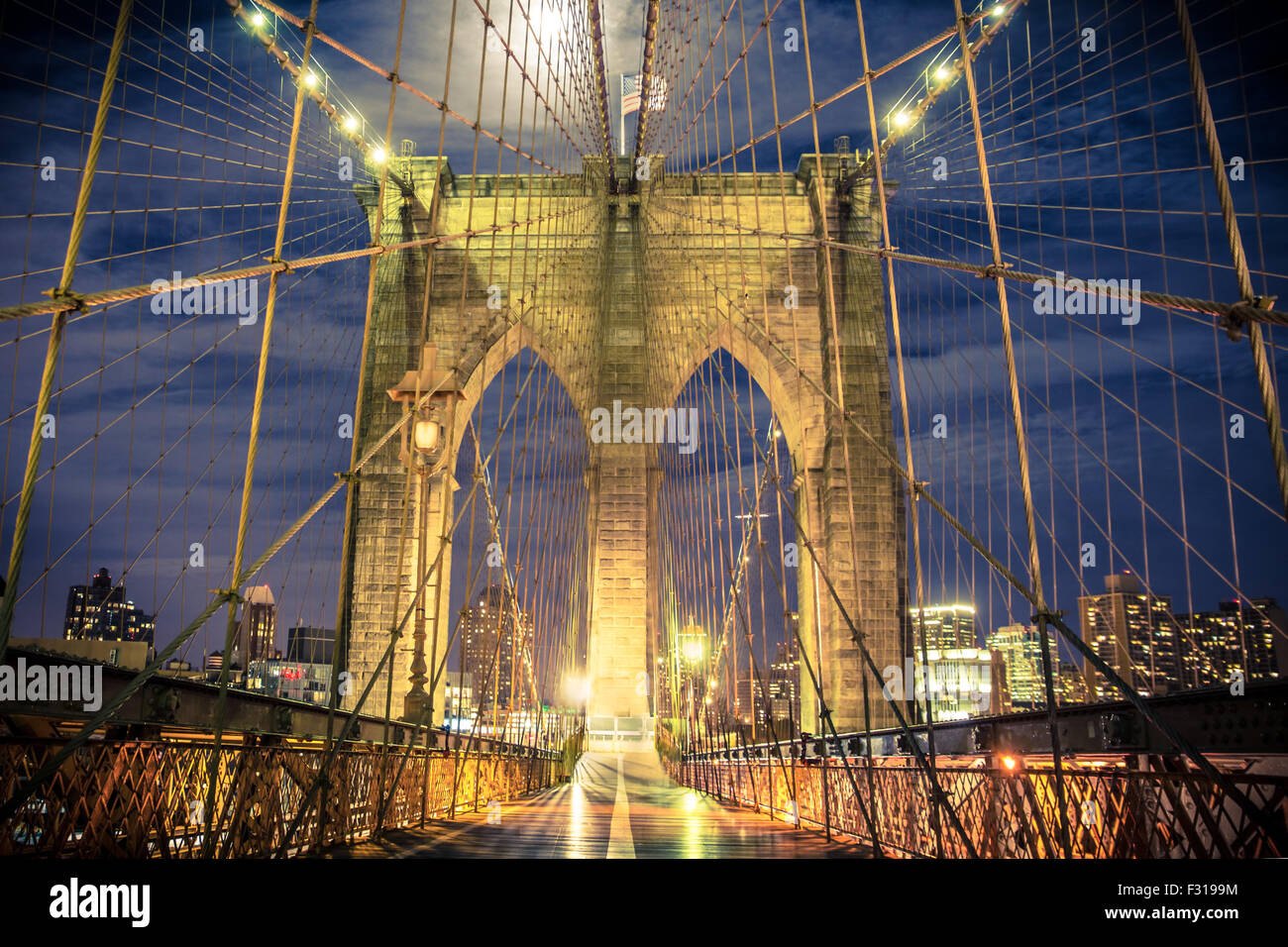 View of historic Brooklyn Bridge at night seen from the pedestrian walkway Stock Photo