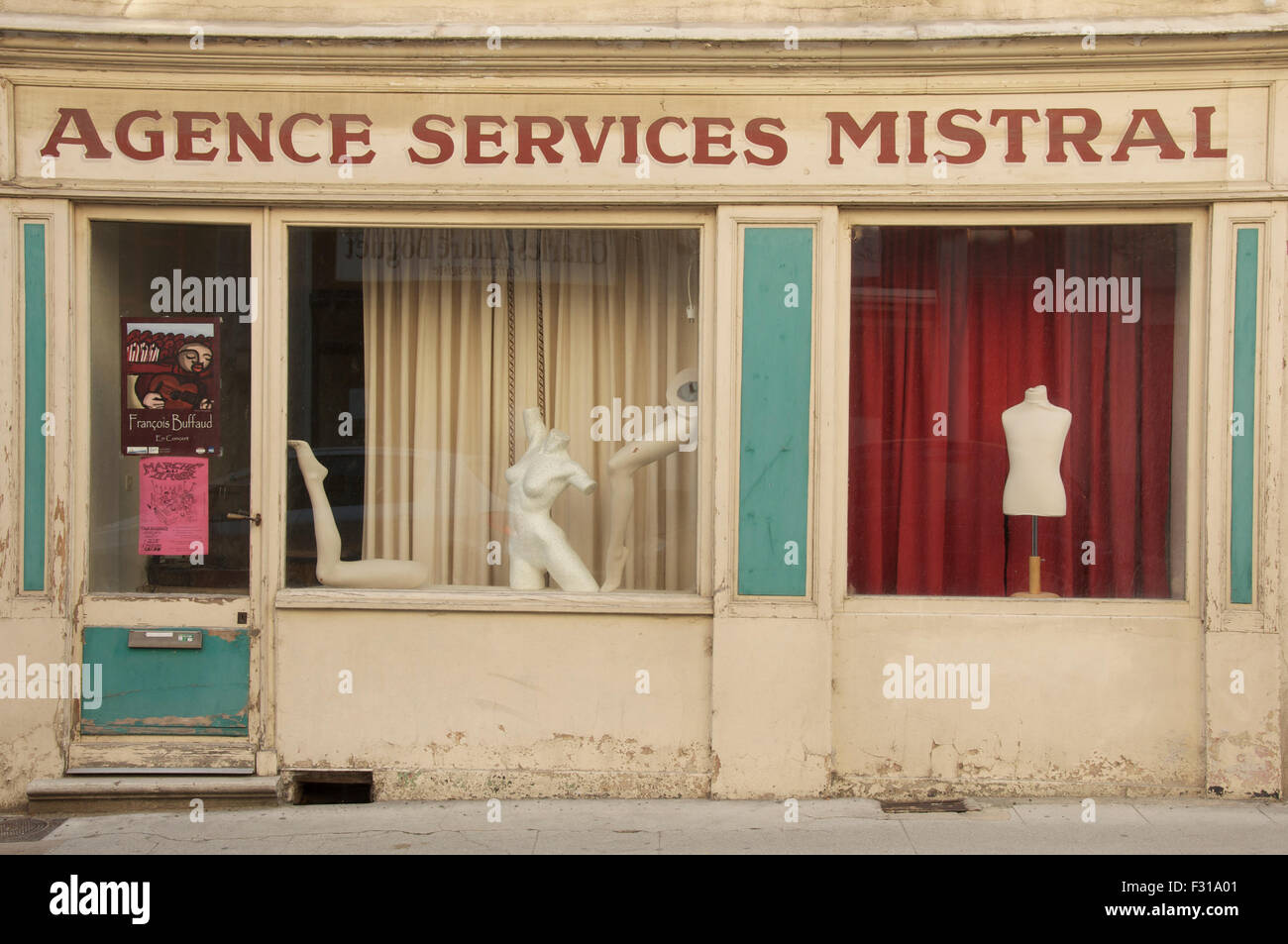 Windows of a vacant shop adorned with a quirky surreal display of mannequin parts and a tailor’s dummy. Crest, La Drôme, France. Stock Photo
