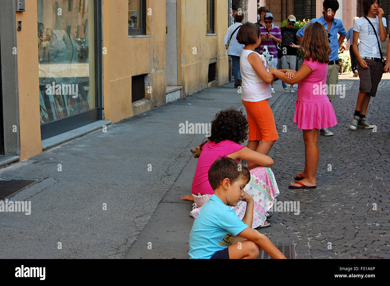 Italian children sitting and playing in a street in Vicenza, Italy. Stock Photo