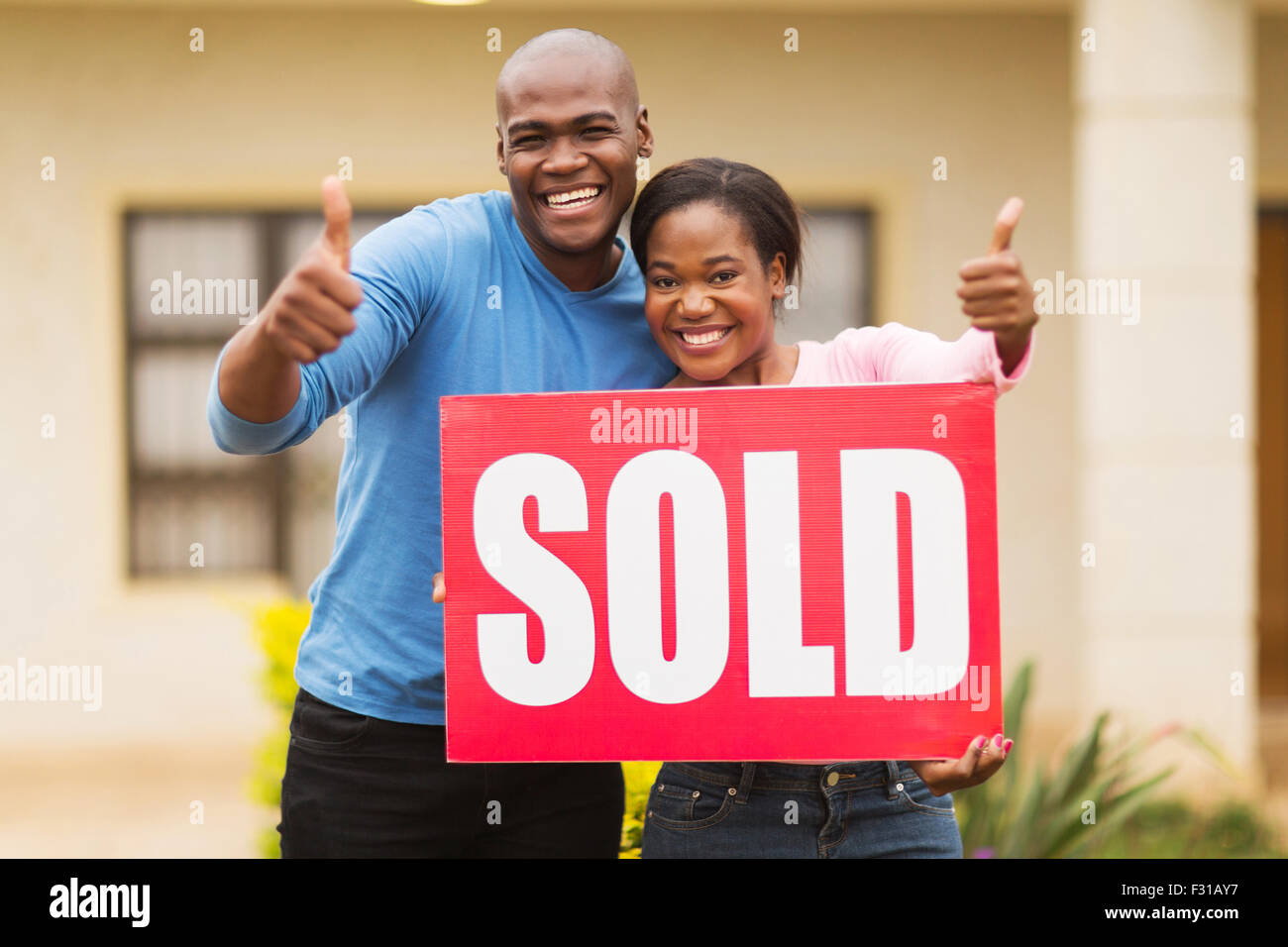 happy African couple outside home with sold sign giving thumbs up Stock ...