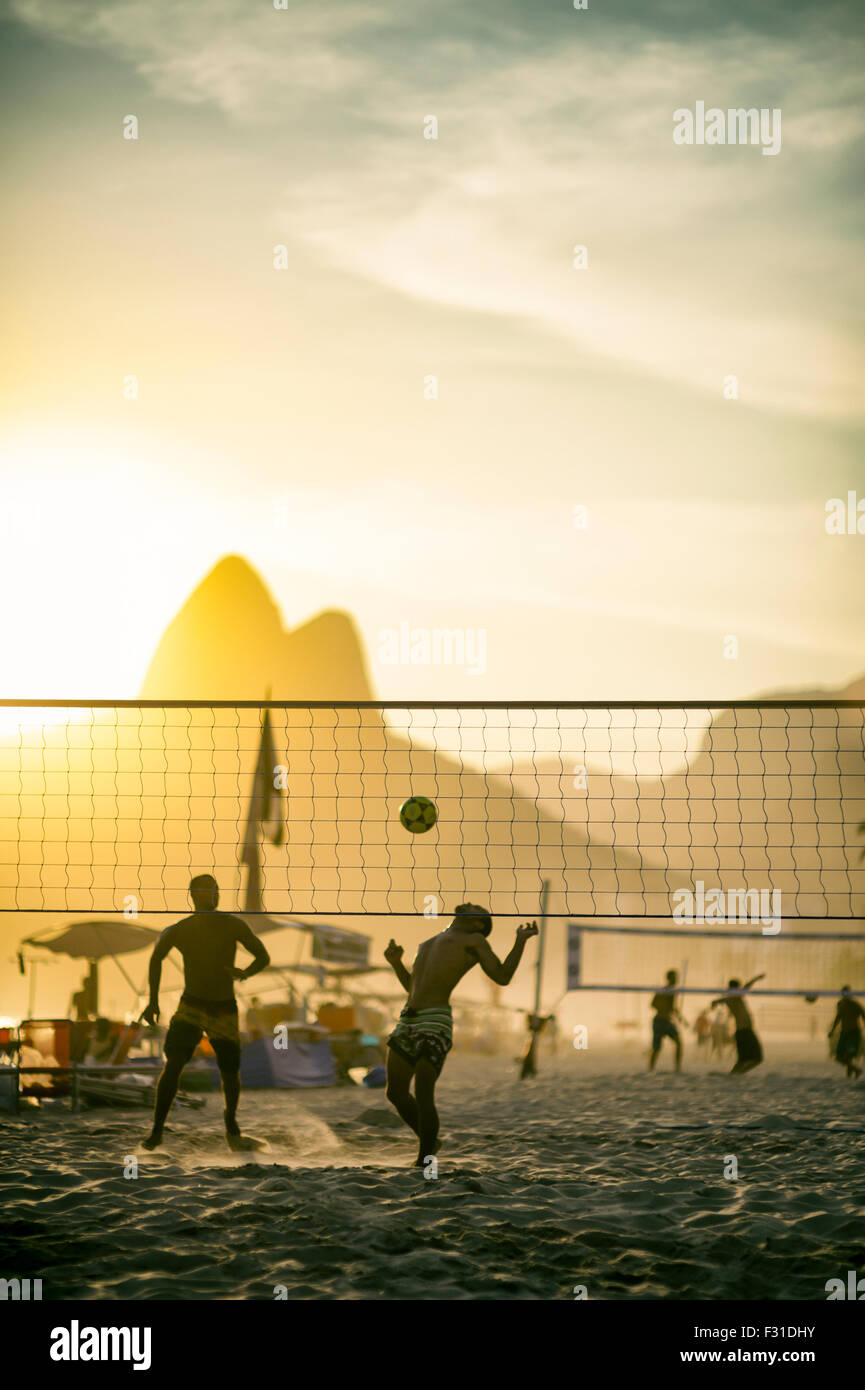 Silhouettes of Brazilians playing a beach ball game in the sand between volleyball nets in Rio de Janeiro, Brazil Stock Photo