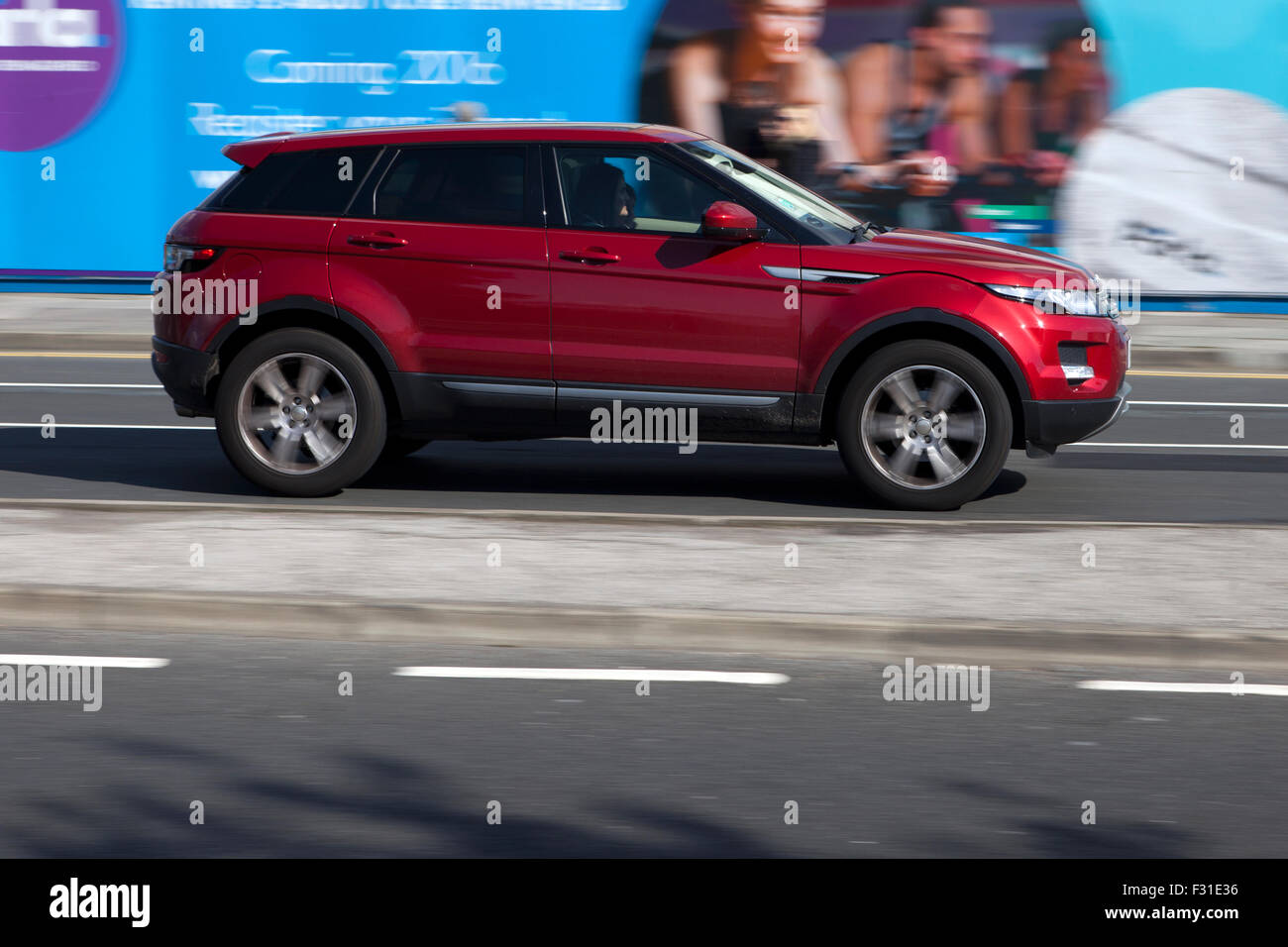 A blurred moving Red Range Rover Evoque at speed motion blur on 'The Strand' at Liverpool One, Liverpool, Merseyside, UK Stock Photo