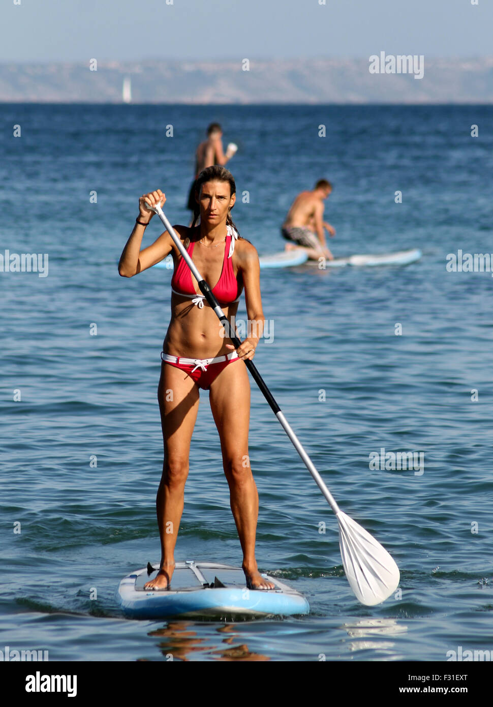 PALMA NOVA BEACH, MAJORCA, SPAIN - 25th August 2015: Palma Nova beach resort on the 25th August 2015. A young woman is paddle bo Stock Photo