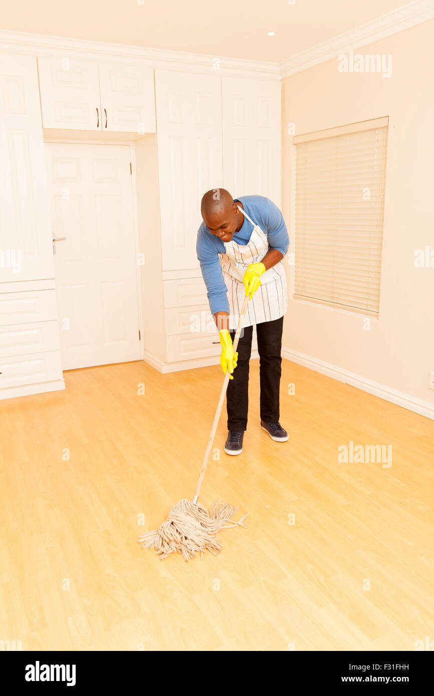 young African man mopping the floor in his empty apartment Stock Photo