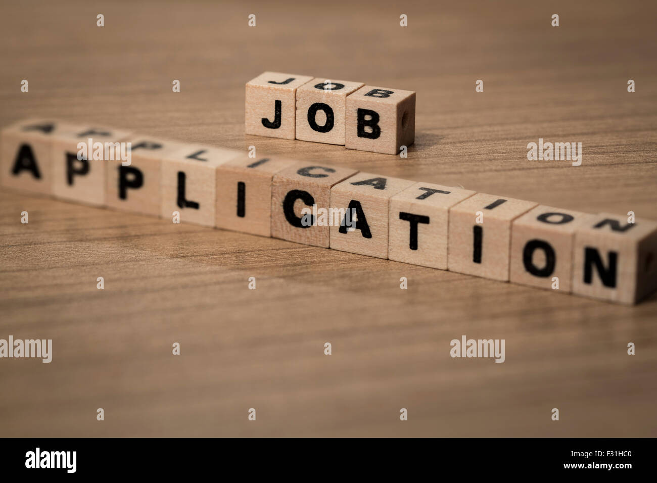 Job Application written in wooden cubes on a desk Stock Photo